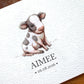 A close-up of a personalized baby shower card featuring a watercolor illustration of a black and white calf. The card is printed with the name 'AIMEE' and the date '06.