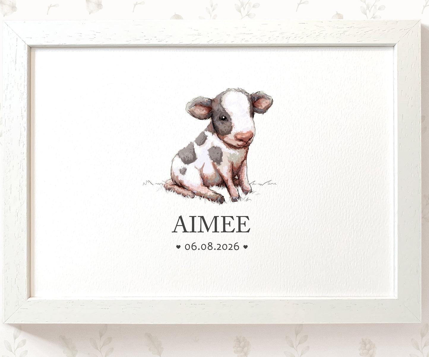 A framed personalized watercolor print featuring a cute black-and-white calf illustration with the name 'AIMEE' and the date '06.08.