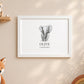 A framed personalized elephant art print hanging on a beige wall, featuring a gray watercolour-style elephant illustration with the name 'OLIVE' and the date '06.08.
