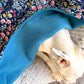 Dog resting under handmade cotton and teal fleece dog blanket showing soft underside